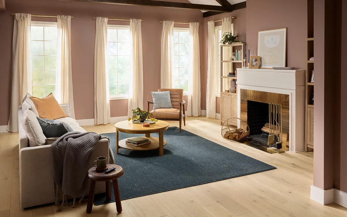 Light wood flooring in a cozy living room with a fireplace and blue area rug | Kay Riley Carpet & Flooring