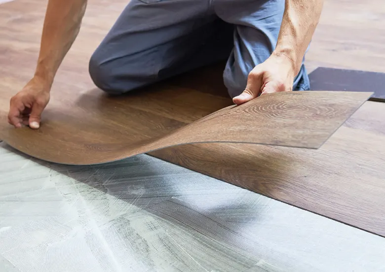 Professional installing a flexible wood-look flooring plank over an existing floor | Kay Riley Carpet & Flooring