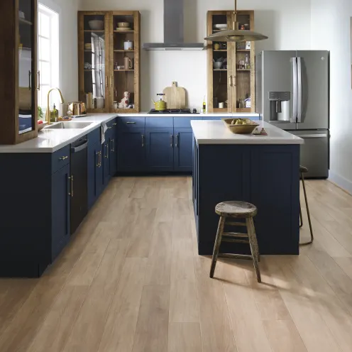 Wood-look vinyl flooring in a modern kitchen with blue cabinets and natural light | Kay Riley Carpet & Flooring