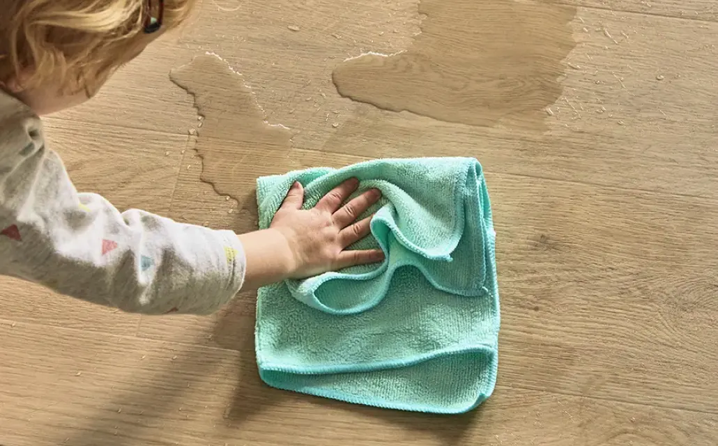 Child wiping a liquid spill from vinyl flooring with a microfiber cloth | Kay Riley Carpet & Flooring